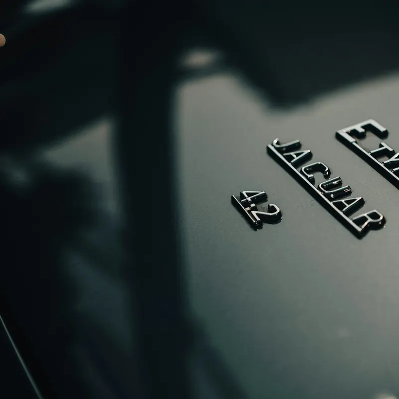 Шильдик Jaguar E-Type 4.2 на тёмном кузове